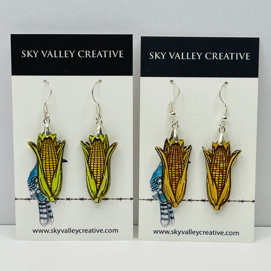 Corn on the cob and Indian corn earrings cut from maple on display cards with 'Sky Valley Creative' branding.
