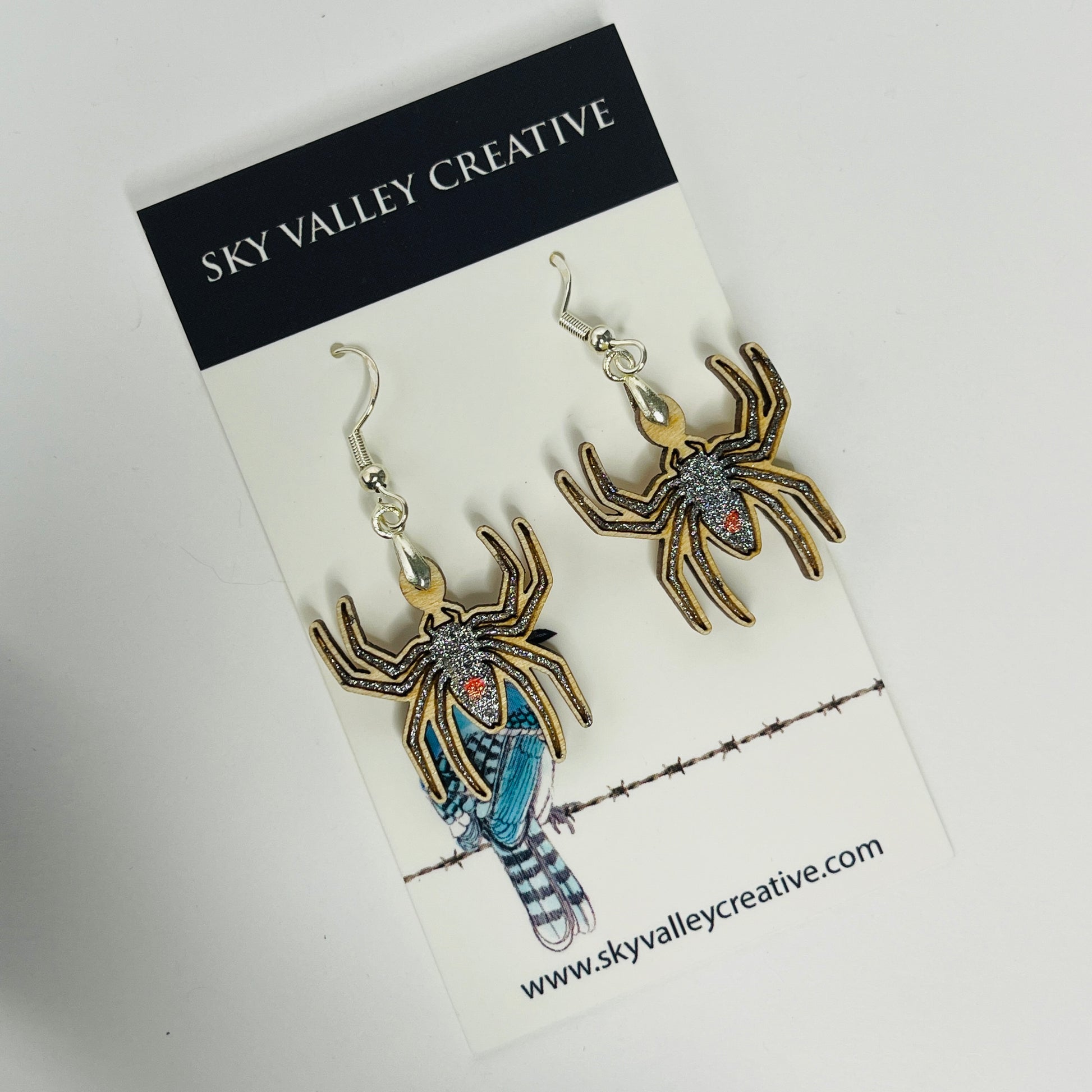 Spider-shaped earrings on a 'Sky Valley Creative' branded card.