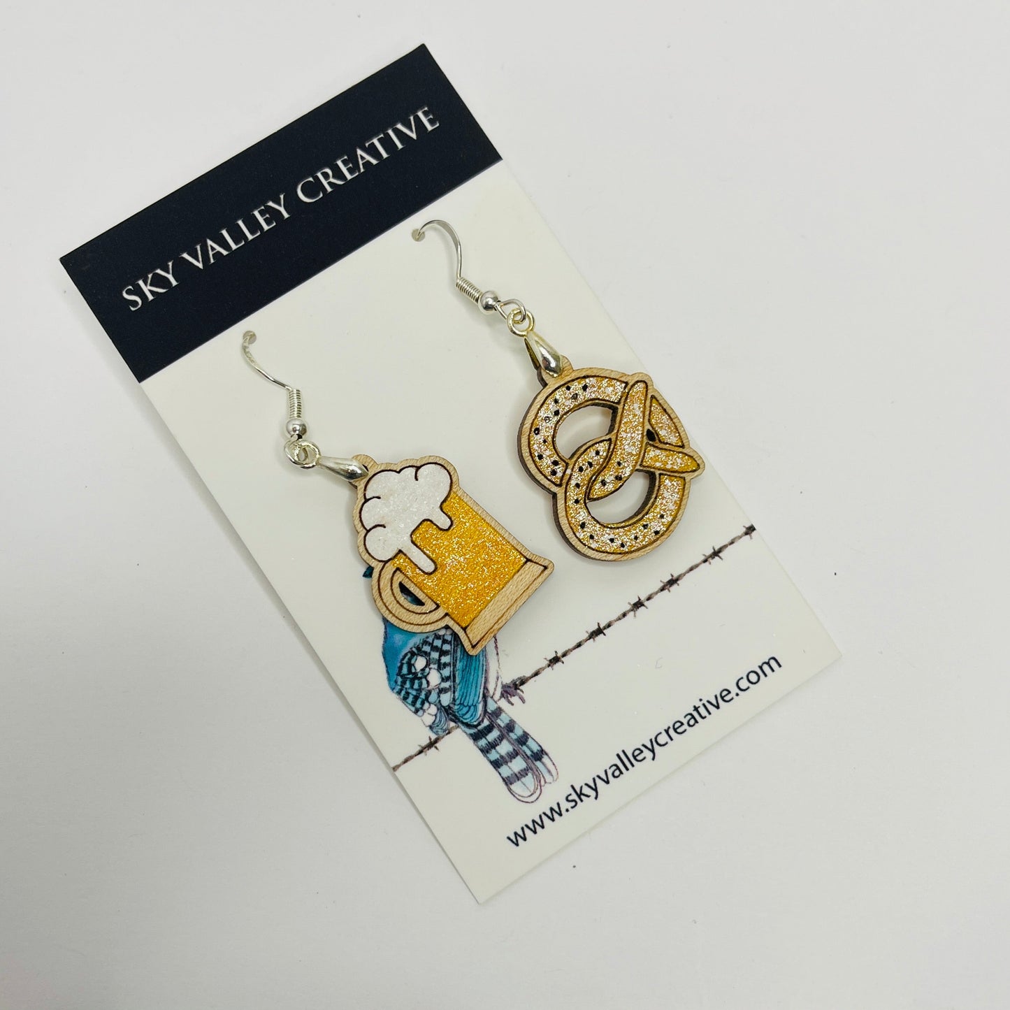 Pair of Wurstfest earrings on a 'Sky Valley Creative' branded card. Beer and Pretzel Dangles.